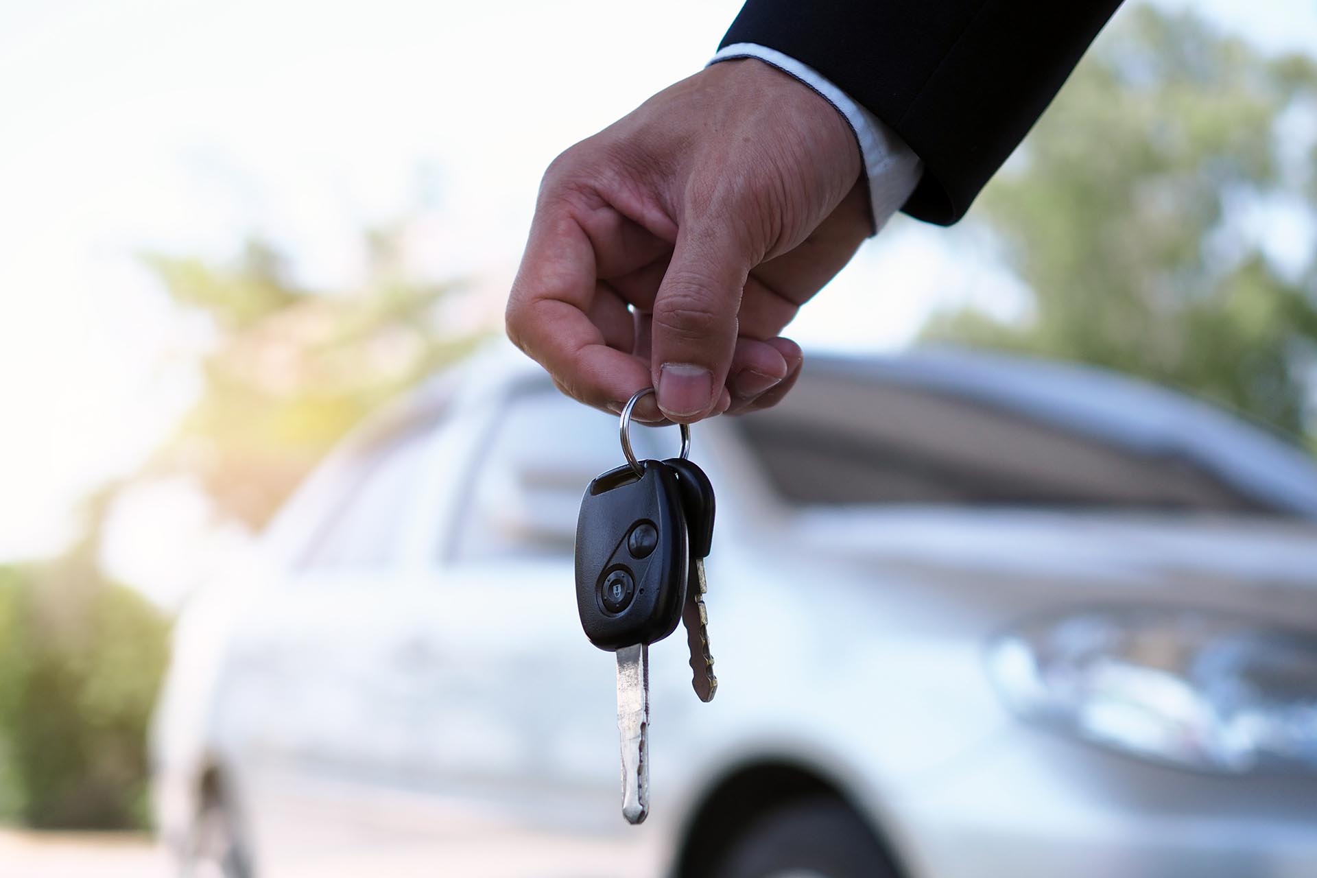 The car owner is handing the car keys to the buyer in a repossession.